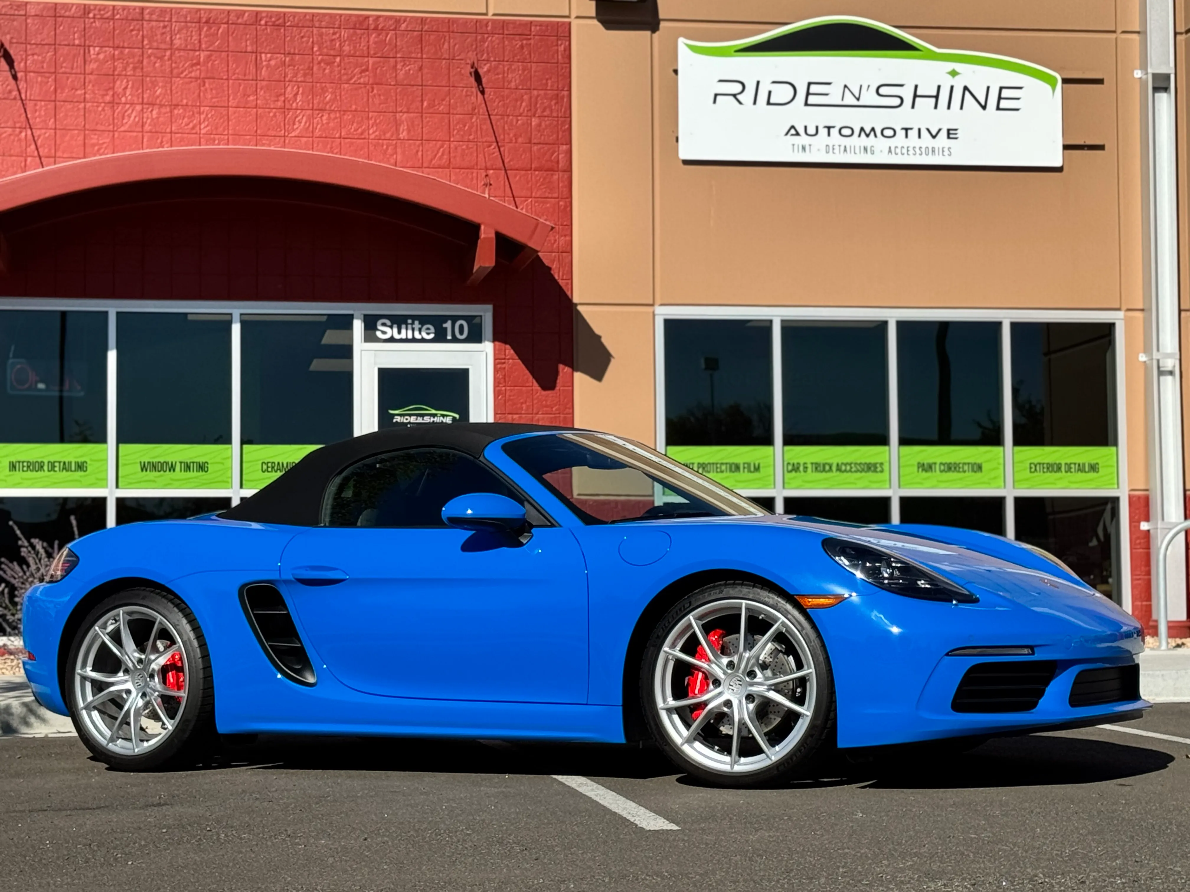 A blue Porsche 718 Boxster with a fresh ceramic coating parked outside the Ride N' Shine shop