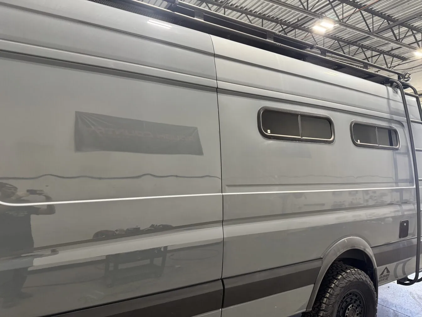 The glossy side of a grey adventure van reflecting the studio lights after a ceramic coating