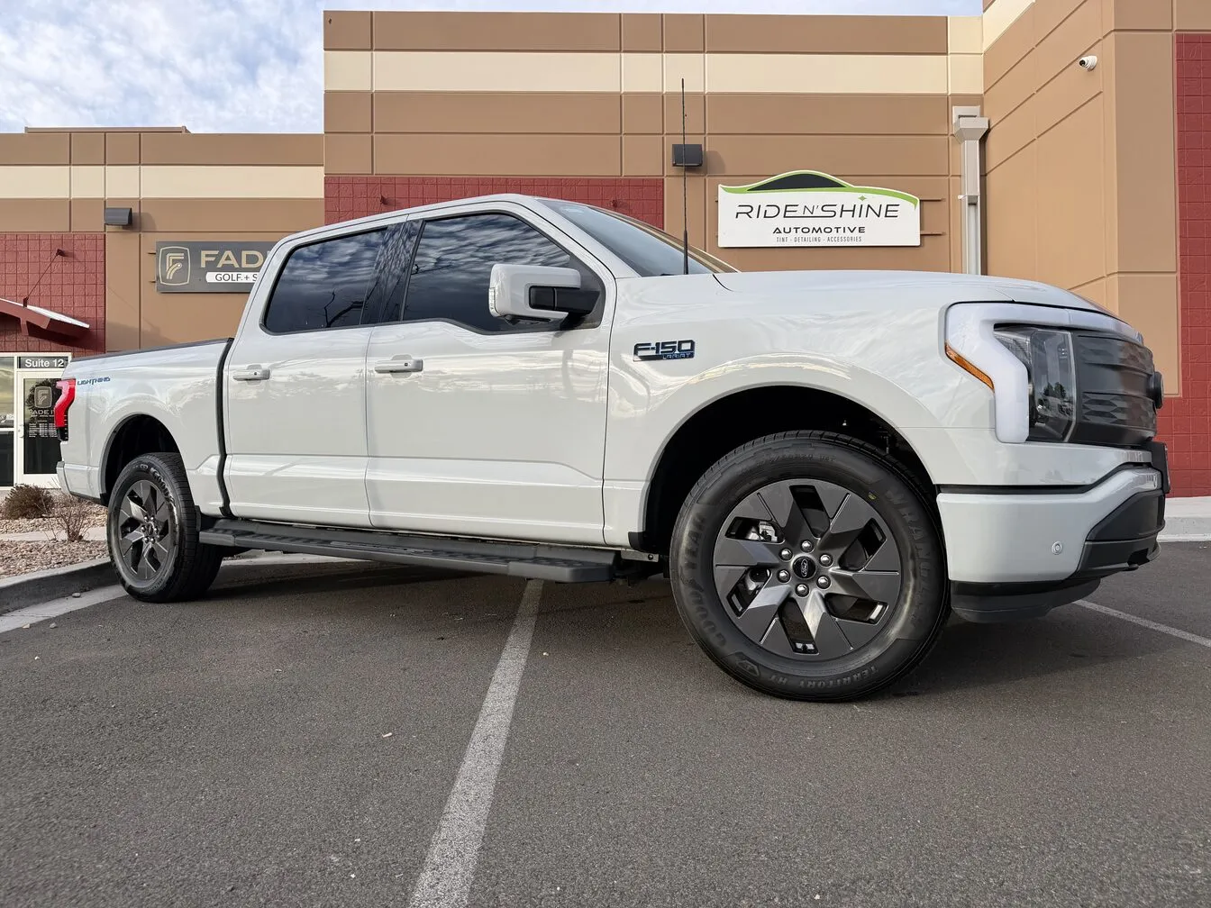 A white Ford F-150 Lightning parked outside the Ride N' Shine storefront