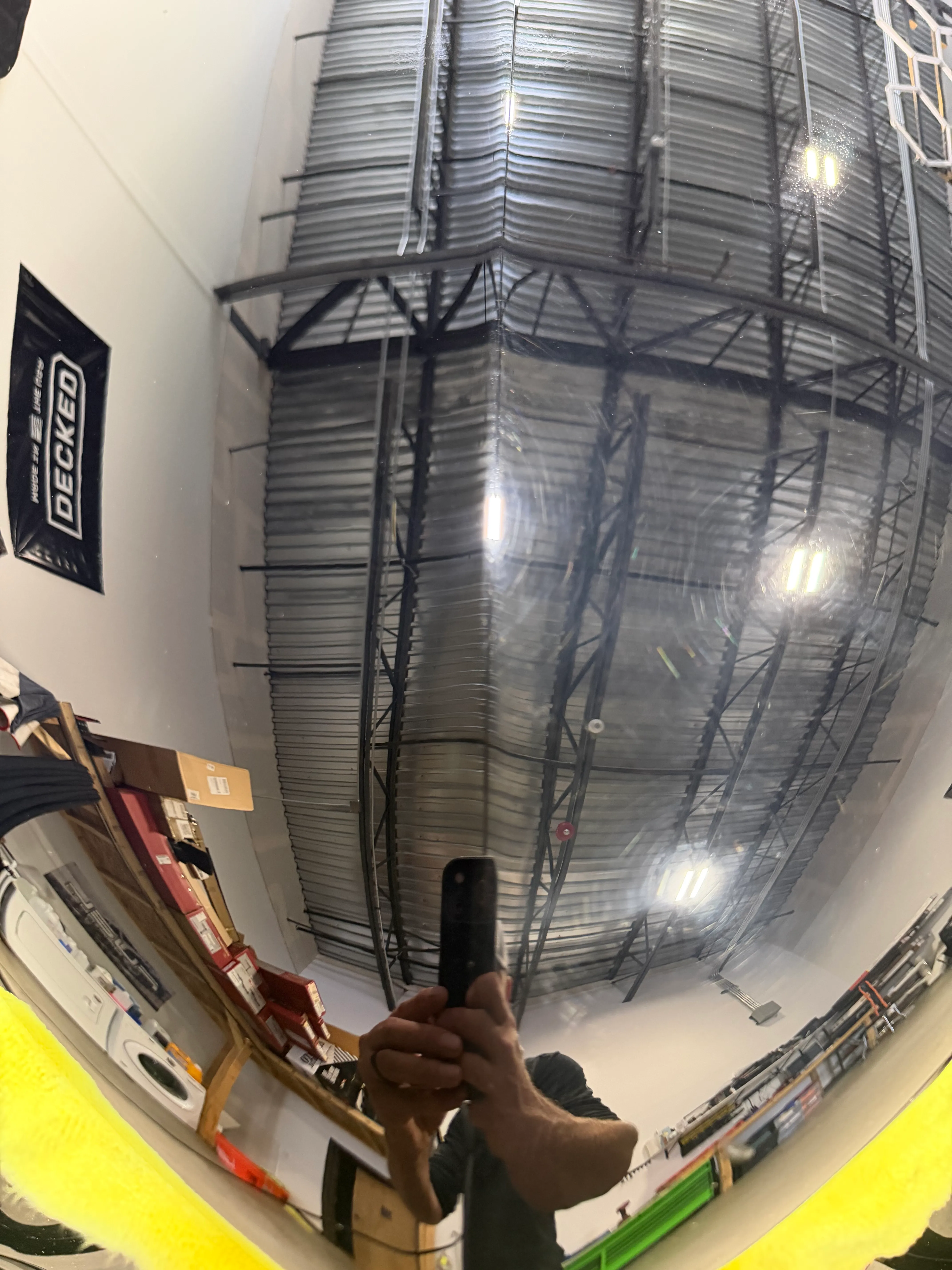 A corrected panel reflecting the shop's ceiling trusses and light bars as an unbroken mirror