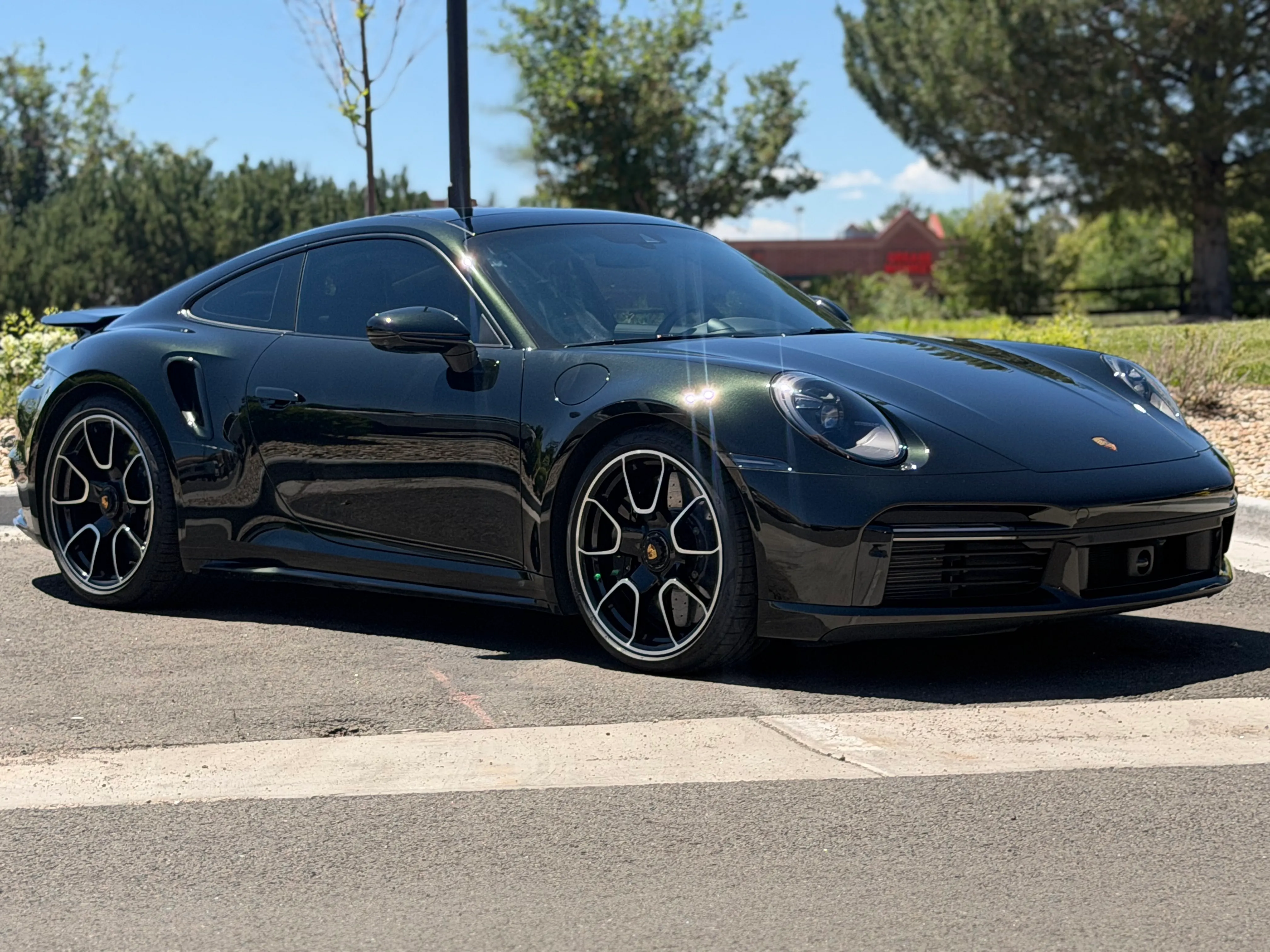 A dark green Porsche 911 Turbo S with paint protection film parked outside the Ride N' Shine shop