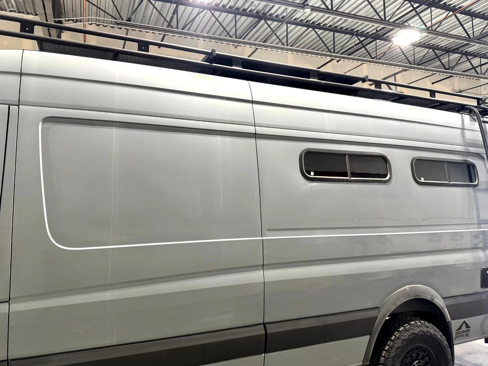 The Sprinter’s tall side panels in the shop during the job, under lights for paint correction and coating