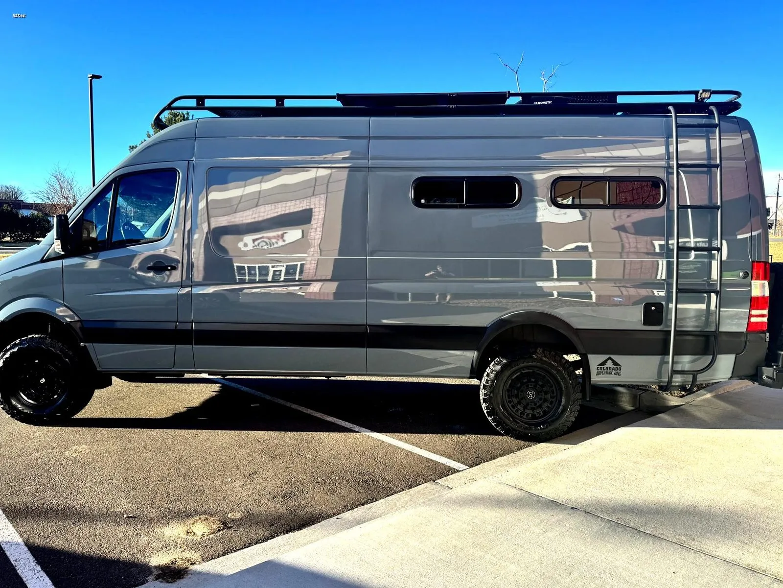 Mercedes Sprinter adventure van with a roof rack parked outside under a blue sky, its freshly ceramic coated paint holding a deep gloss