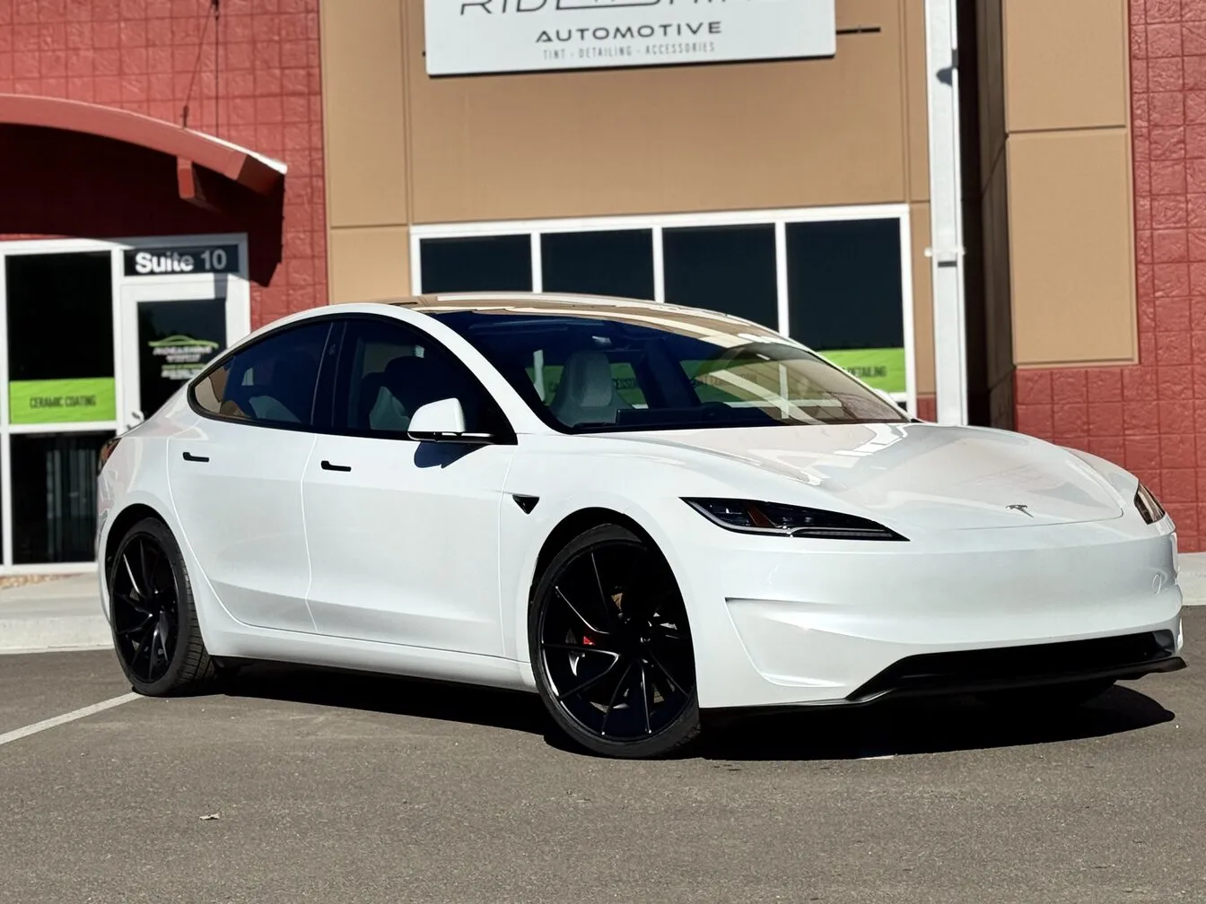 A white Tesla Model 3 with tinted windows outside the Ride N' Shine storefront