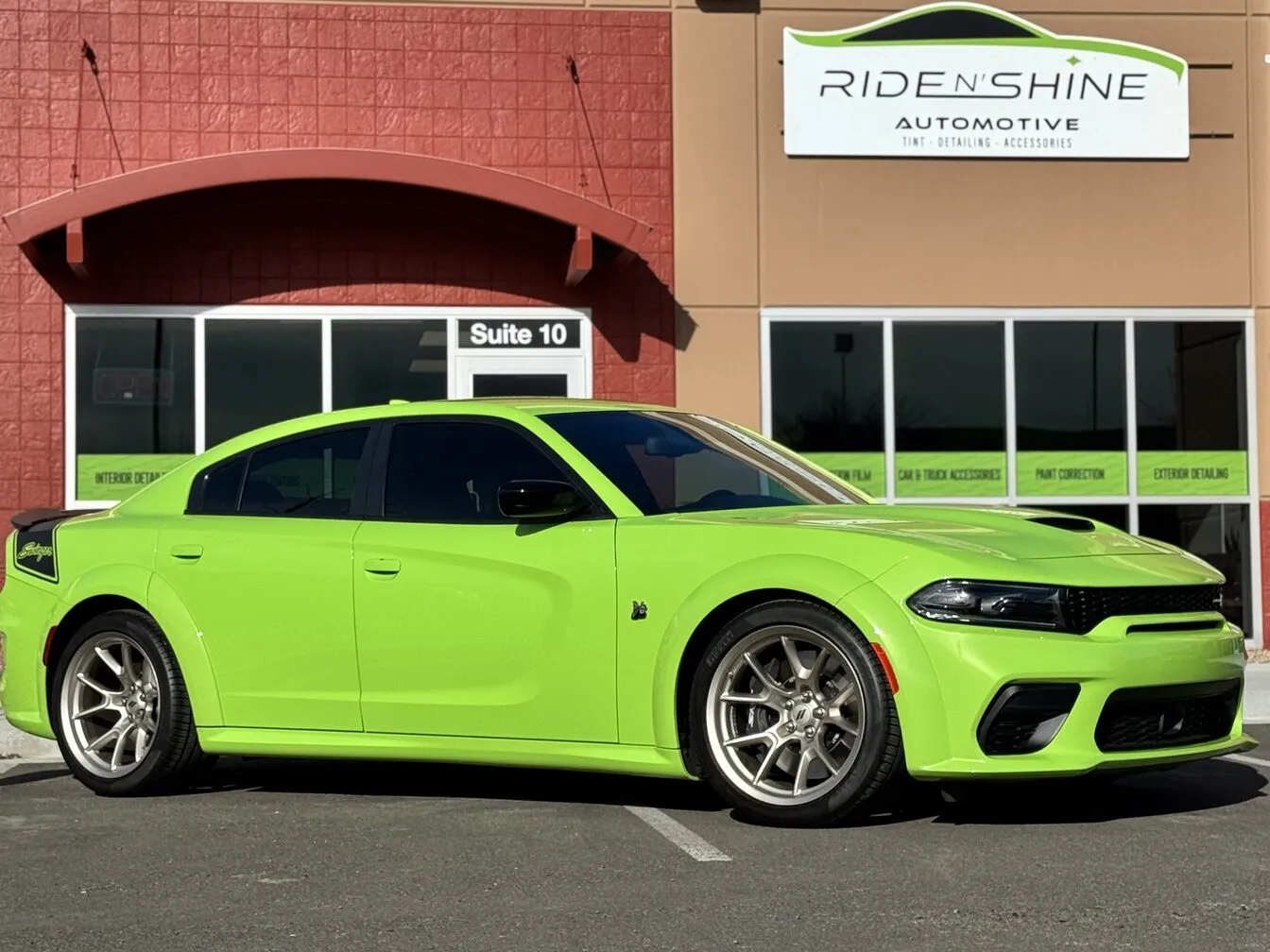 A lime green Dodge Charger Scat Pack with tinted windows outside the Ride N' Shine storefront