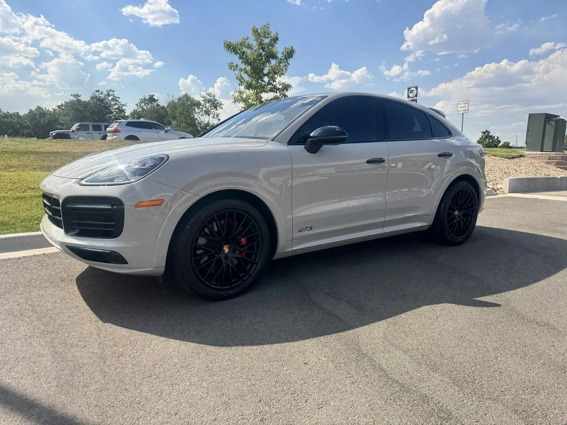 A chalk grey Porsche Cayenne Coupe GTS with tinted windows, parked outside on a clear day