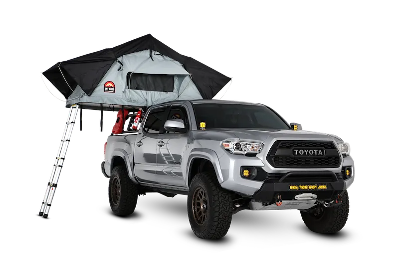 A silver Toyota Tacoma with a Sky Ridge roof-top tent open on its bed rack and the ladder down