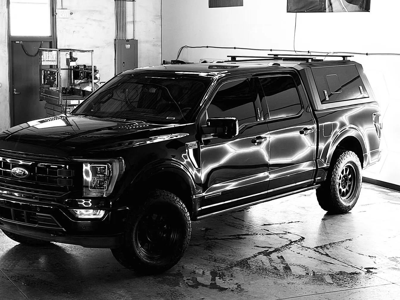 A black and white shot of a Ford F-150 with a camper shell inside the studio