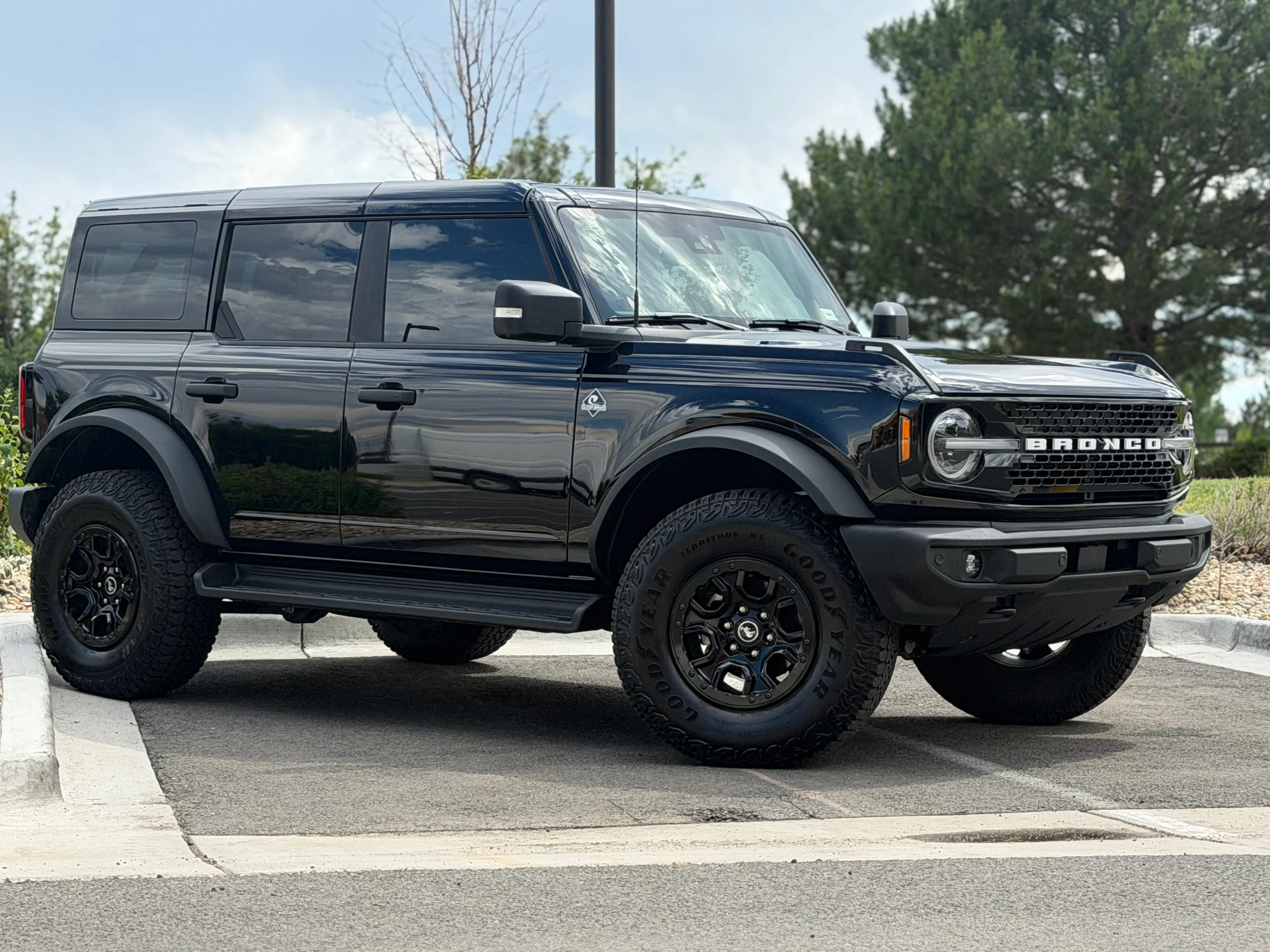 A black Ford Bronco with tinted windows parked on a street on a cloudy day